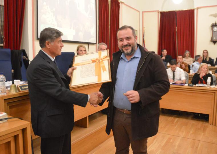 Ο πρόεδρος του Δημοτικού Συμβουλίου Καλαμάτας,  Τάσος Ηλιόπουλος, προσφέρει στον Δημήτρη Μαστραγγελόπουλο, τα δώρα που αντιστοιχούν στο φλουρί της πίτας του Δημοτικού Συμβουλίου, το οποίο του έτυχε